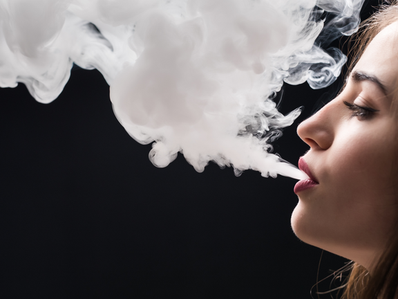 Mujer echando el humo de tabaco por la boca