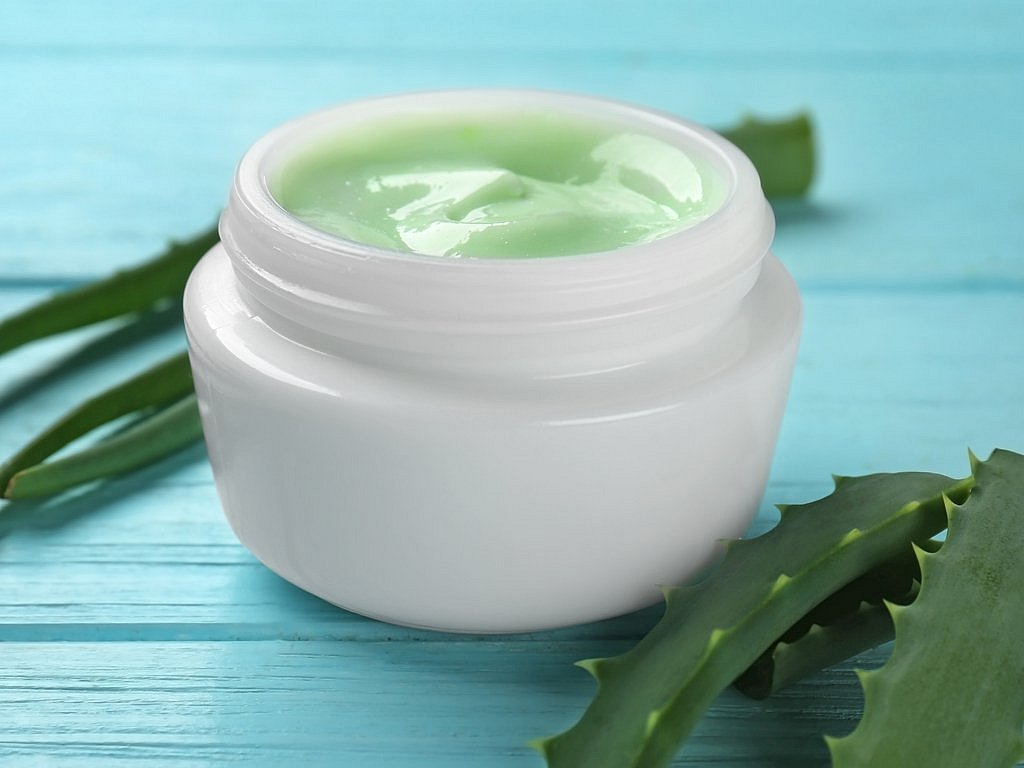 Un frasco de crema hidratante acompañado de ingredientes como aloe vera Un frasco de crema hidratante acompañado de ingredientes como aloe vera